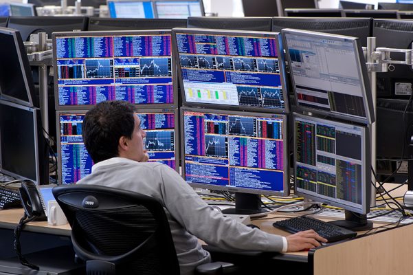 a forex trader analyzing charts on his computer screens
