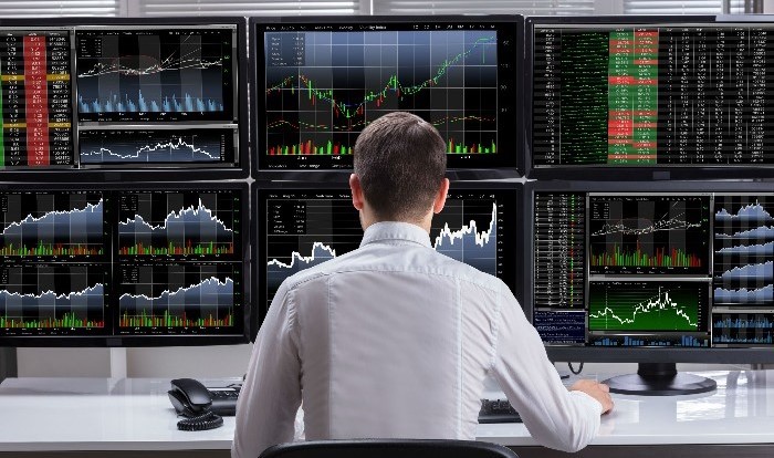forex trader in front of multiple screens
